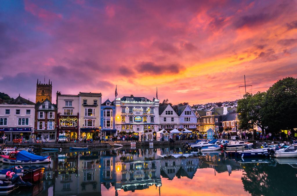 Dartmouth harbour at sunset during the Royal Regatta, with sailing boats on the River Dart and golden light reflecting on the water